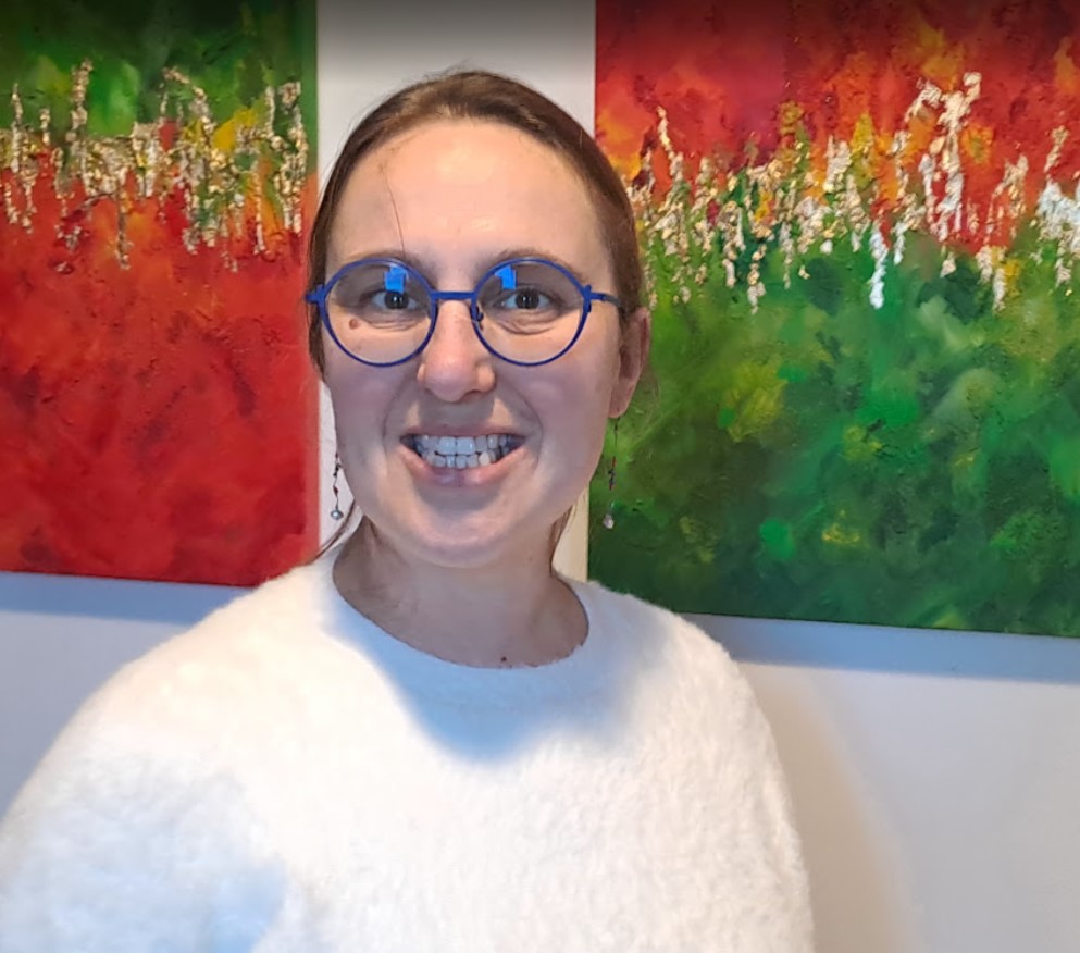 Céline sourit devant 2 toiles rouges et vertes.
